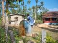 A woman climbs up a water tank to fetch water due to lack of access to pipe water connection (Image Source: India Water Portal Flickr Album)