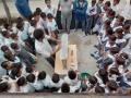 Children gather around Ashvath Singh as he demonstrates hydrogeology.