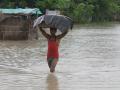 A man wades through knee-deep water with his belongings. (Source: 101Reporters)