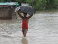 A man wades through knee-deep water with his belongings during the flood. (Source: 101Reporters)