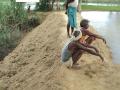 People of Laksena watch over their temporary dam