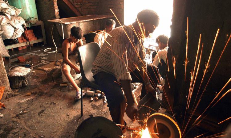 Boys sort discarded computer parts as sparks fly from a grinding machine.  (Image: Greenpeace, Flickr Commons; CC BY-ND 2.0)