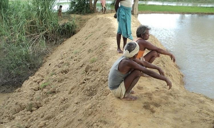 People of Laksena watch over their temporary dam