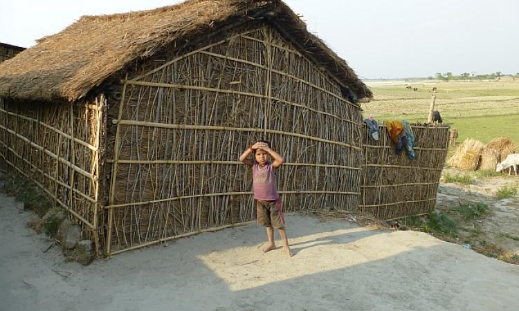 A boy stands outside his home on a spur